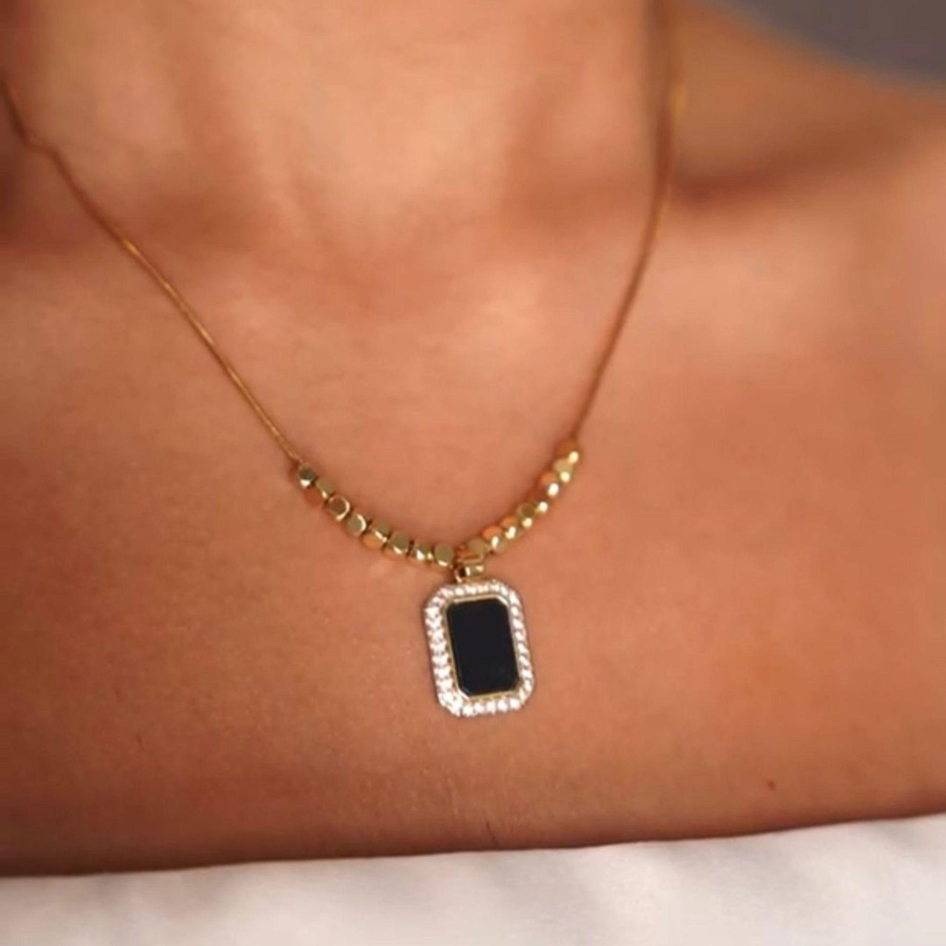Close-up of black pendant on gold plated necklace